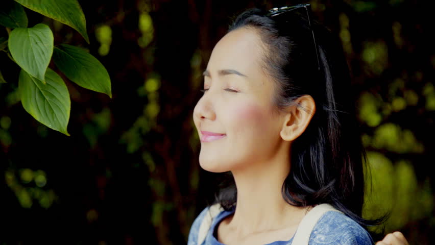 Slow motion Close Up of a young Asian beautiful Woman breathe deeply in a forest to enjoy the beauty and purity of nature in Doi Inthanon Chiang Mai, Thailland.