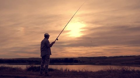 Silhouette of man enjoying fishing with beautiful sunset.