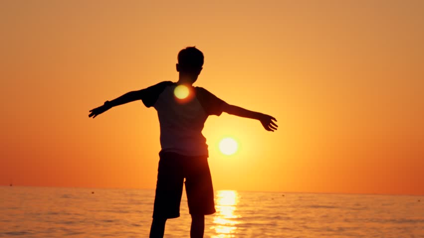 Silhouette of a boy standing on the beach, the concept of happiness, dream, human space, children