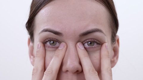 Close up macro of brunette woman doing exercise for strengthening the lower eyelids. Isolated on the white background.