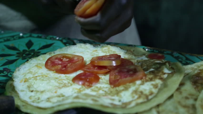 A cook in a Uganda restaurant cuts tomatoes for a wrap