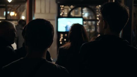 Friends watches football on TV in a sport bar silhouette in dark