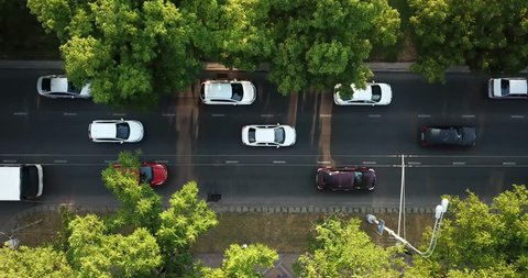 Aerial Drone Flight top down View of freeway busy city rush hour heavy traffic jam highway.  Aerial view of the vehicular intersection,  traffic at peak hour with cars on the road, fly under trees.