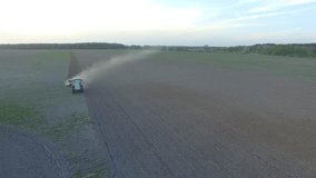 Tractor plows big field at sunset (aerial footage, overflight, frontal)