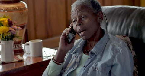 Frustrated, mad, senior black woman in her 50s or 60s talking on her mobile phone displeased at the annoying caller on the other end