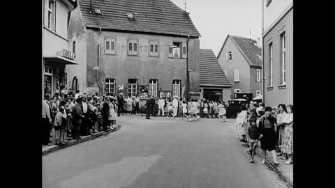 CIRCA 1962 - Audie Murphy watches a Redstone rocket get towed through a German town. Civilians of all ages also look on in awe.