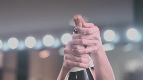 
Opening champagne. Popping champagne. Hands opening champagne. Happiness. Celebration. Colors. Blurred background. Lights background. Slow motion.