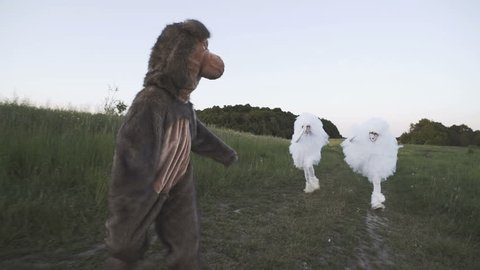 Two funny clowns mime in white air suits are chasing a ridiculous bear along a country road in the field. HD