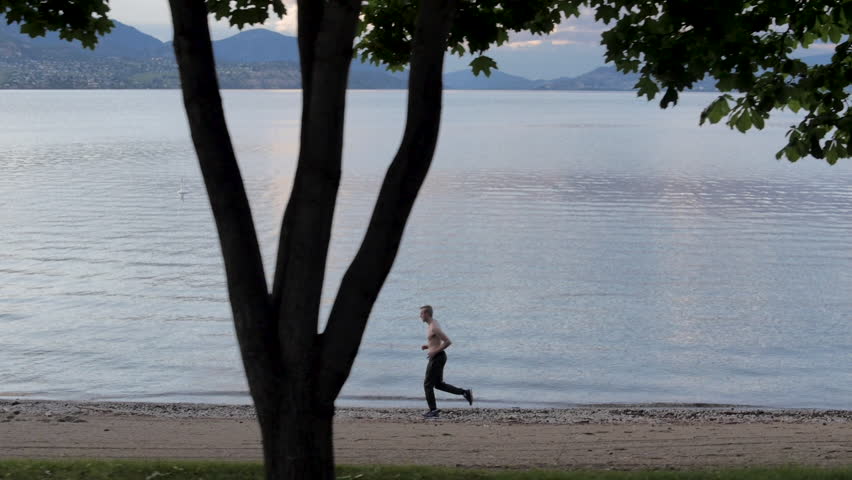 Slow Motion Shirtless Man Jogging Along the Shoreline