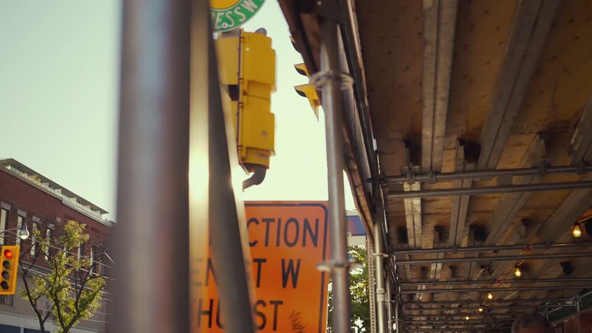 Camera tracks horizontally left as the sun shines from behind a street post and into the camera lens