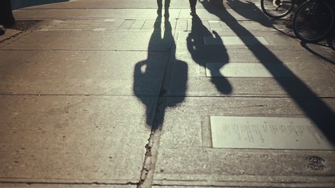 The evening sun casts shadows of two people walking down Queen Street West in Toronto SLOW MOTION
