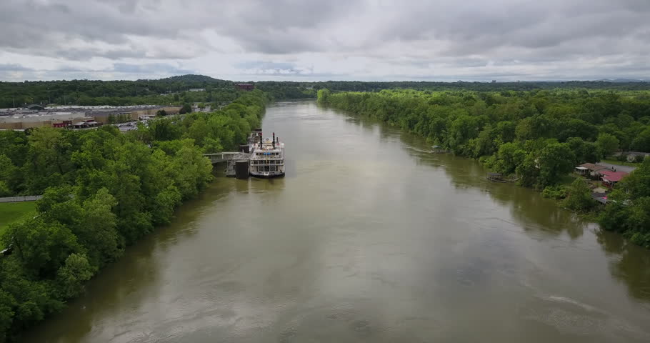 Aerial footage of a riverboat docked on the bank of the muddy Cumberland river in Nashville, Tennessee.