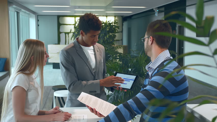 Multiracial men and woman working on report. Group of diverse woman and men with tablet in modern office hall having work with documents and statistics. | Shutterstock HD Video #1013575646