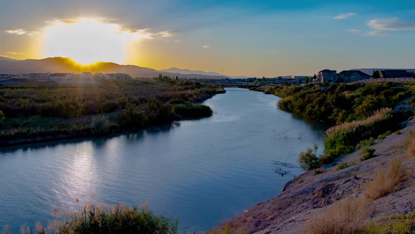 Static time lapse of a beautiful river and ladscape at sunset as the scen transitions to night