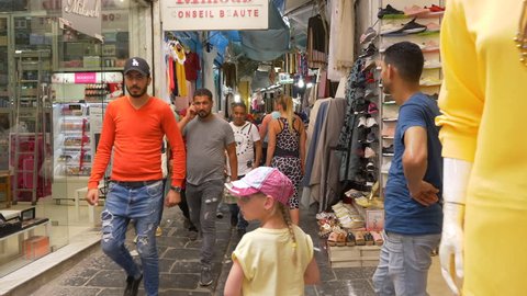 Tunis, Tunisia - 06 June 2018: tourist people walking and looking souvenirs and gifts on local market. Tourists people on traditional arabian bazaar.