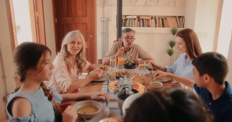 Three-generation multi-ethnic family with grandparents sitting around table and eating healthy lunch at village cottage