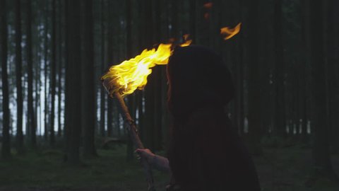 Woman walking trough the forest with a torch