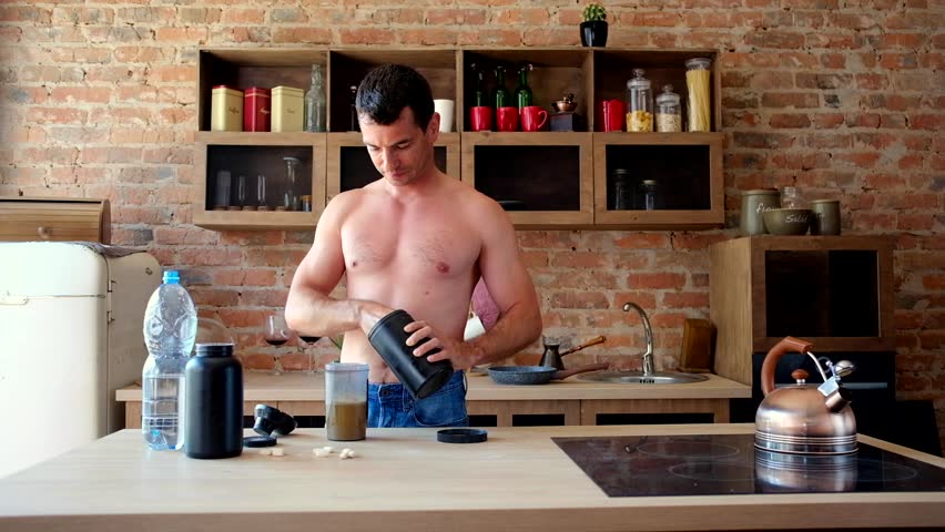 Young attractive man preparing a protein cocktail in the kitchen