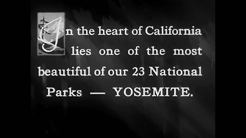 CIRCA 1933 - A tourist drives into Yosemite National Park, under the Arch Rocks.