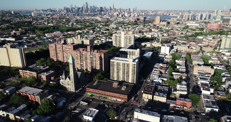 Aerial panorama reveals Jersey City neighborhoods with Manhattan rising across the Hudson River in the distance, 2018.