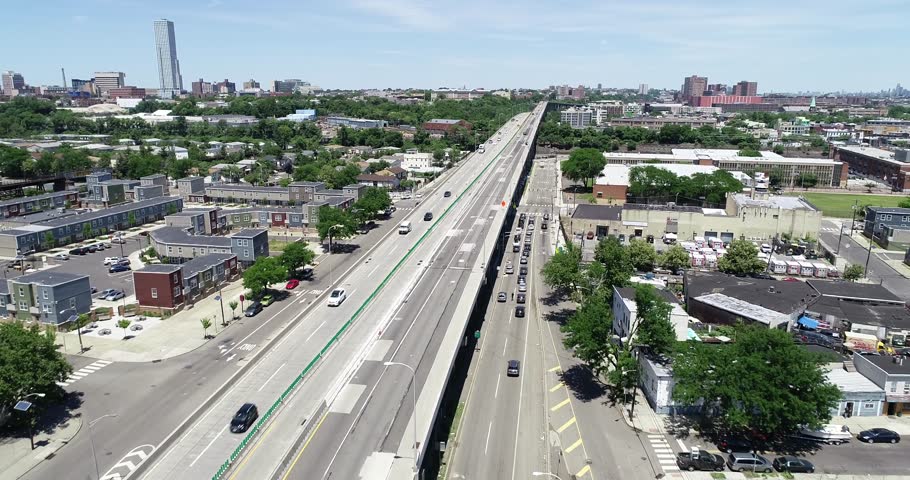 Traffic travels an elevated Jersey City highway above homes and rail yards, 2018.