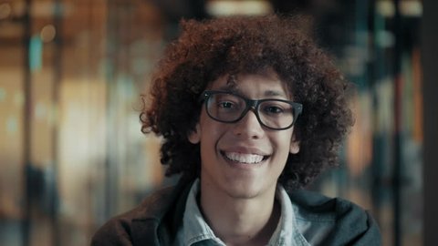 Portrait of happy smiling african young male in glasses close up face of cheerful black guy with fluffy curly black hair cute creative afro man in modern start up office looks and smiles positive mood
