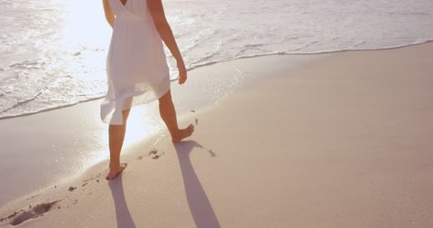 Beautiful woman wearing white dress walking on beach at sunset in slow motion RED DRAGON
