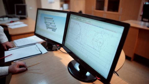 Engineers view the drawing of the part on the screen of the monitor