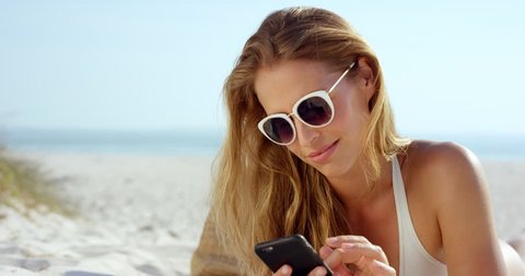 Beautiful woman using phone text messaging conversation lying on beach suntanning RED EPIC DRAGON