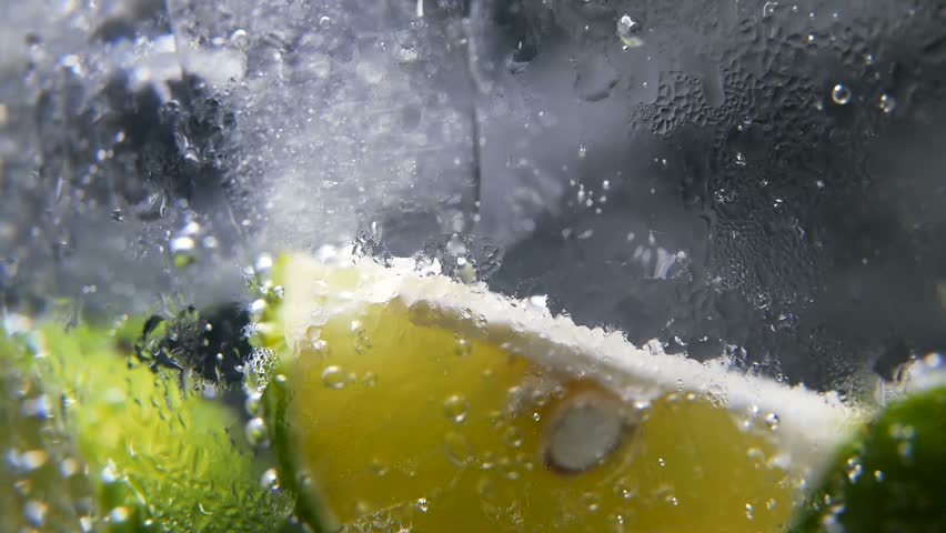 Macro close-up,refreshing soda tonic fizzy water, lime in Glass, ice. Slice of lemon, mineral bubbles. Detox or thirst concept. Healthy, dietary nutrition. Cold lemonade mojito drink. Black background | Shutterstock HD Video #1013636051
