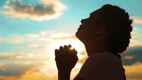 girl praying. girl folded her hands in prayer silhouette at sunset. slow motion video lifestyle. Girl folded her hands in prayer pray to God. asks forgiveness for sins of repentance. believing girl