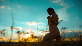 Girl folded her hands in prayer silhouette at sunset. slow motion video. Girl folded her hands in prayer pray to God. girl praying asks forgiveness for sins of repentance. believing girl. concept