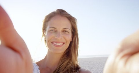 Beautiful woman taking selfie using phone on beach at sunset smiling and spinning on vacation slow motion RED DRAGON