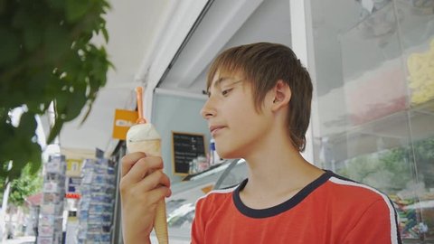 Close-up of 15-years-old teen boy licking craft ice cream cone on cafe terrace