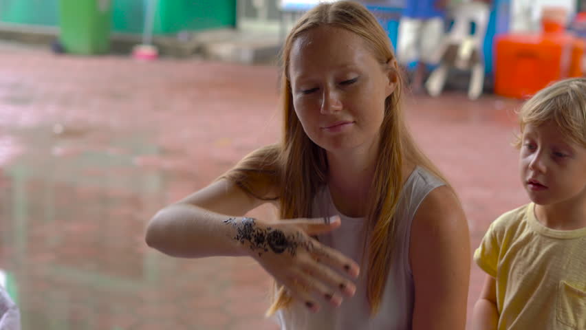 Young woman getting a temporary henna picture of a hindu pattern on a hand