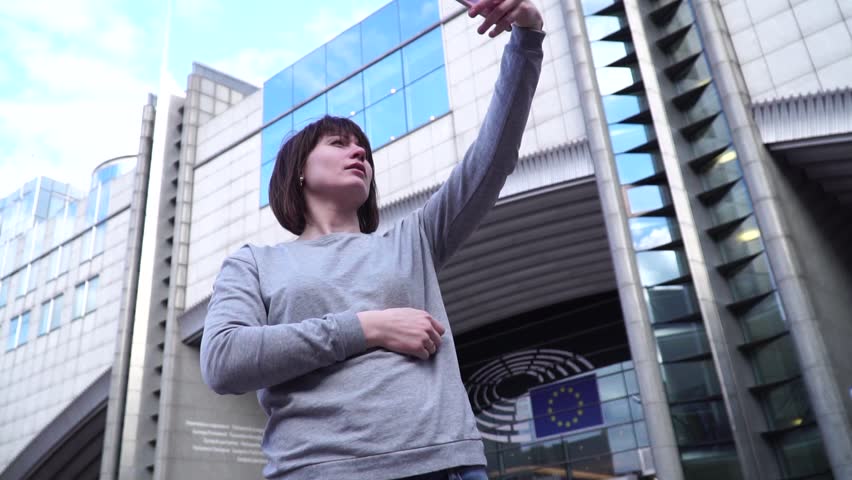 Lady tourist make selfie on smartphone near the European Parliament in Brussels. Belgium. slow motion.