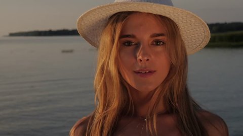 Close-up portrait of a young beautiful girl in a white hat on the beach