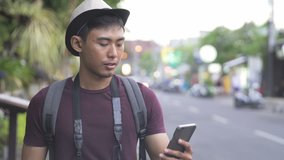 footage of asian traveller video calling with his friends on mobilephone while walking down the street during summer holiday