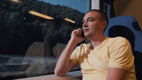 A man is traveling by train. Sits at the window and looks into the smartphone.