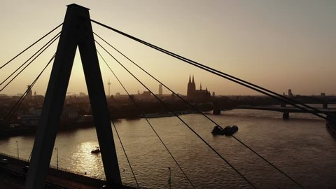 The sun sets over Cologne and makes the silouette appear orange. The cathedral and the Severinsbrücke are in focus.