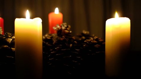 burning candles and pine cones against a dark backdrop in a Christmas scene