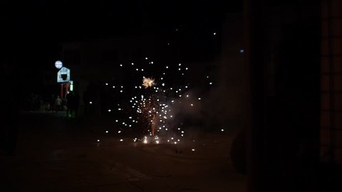 Wide slow motion shot of fireworks going off in the street