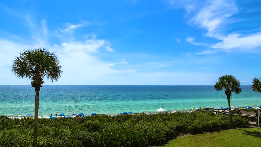 Overlooking lawn and boardwalk and beach under blue sky.