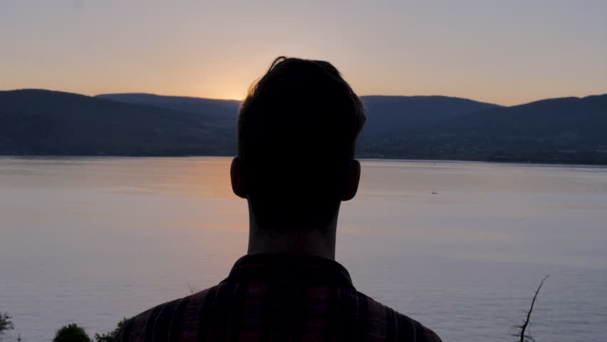 Slow Motion Man Silhouette Standing on Mountain Overlooking Lake