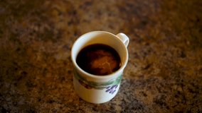 slow motion clip of creamer dissolving into black coffee before stirring