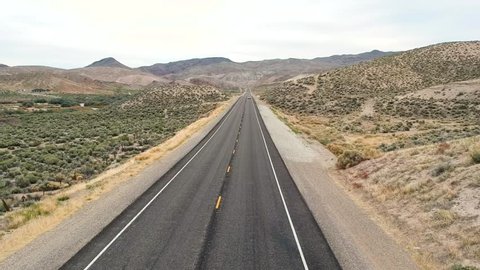 drone shot of a car driving along a very long straight and scenic road