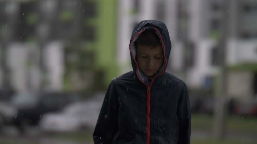 Offended sad boy is standing in the rain and looks into the camera | Shutterstock HD Video #1013707919