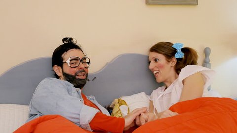 An odd couple (actors in character as kids): a guy talking and a girl agreeing on everything, then going under the covers to have sex. Funny comedy medium close-up shot.

