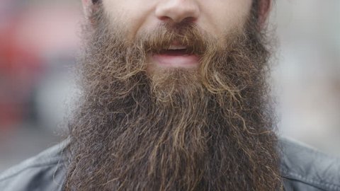 Close up of a man's mouth with a bushy big beard talking to camera