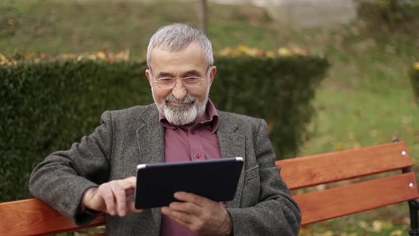 Grandpa use a tablet sitting in the park on the bench Royalty-Free Stock Footage #1013717264